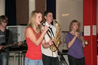 Drie jonge muzikanten met sax, trompet en microfoon